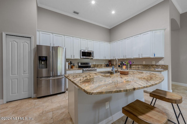 kitchen with appliances with stainless steel finishes, white cabinetry, sink, and a center island with sink