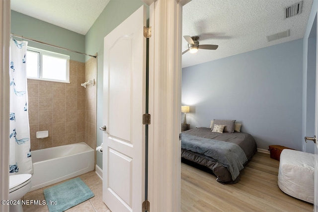 bedroom featuring light hardwood / wood-style floors, a textured ceiling, and ceiling fan