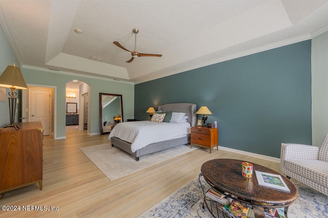 bedroom with crown molding, a raised ceiling, light hardwood / wood-style flooring, and ceiling fan