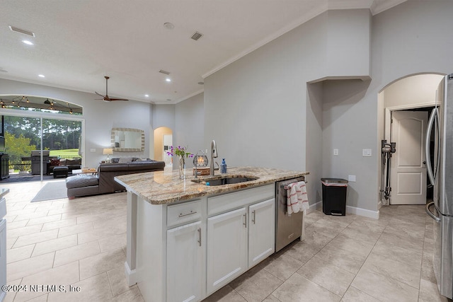 kitchen featuring white cabinets, light stone counters, an island with sink, stainless steel appliances, and sink