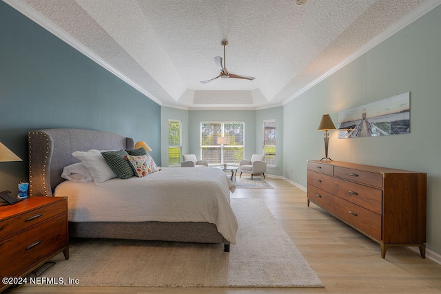 bedroom featuring a raised ceiling, a textured ceiling, ceiling fan, crown molding, and light hardwood / wood-style flooring