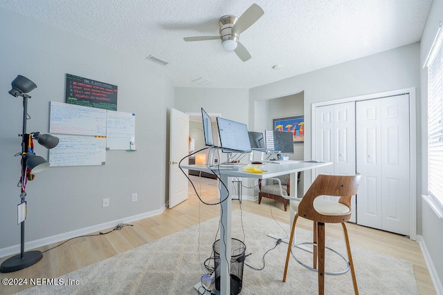 office space featuring a textured ceiling, light wood-type flooring, and ceiling fan