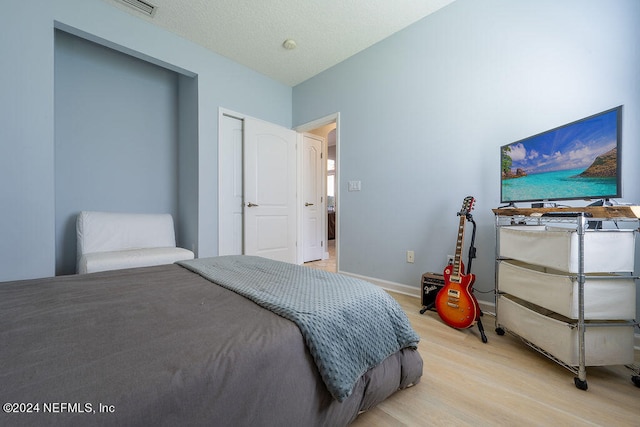 bedroom featuring a textured ceiling and light hardwood / wood-style floors