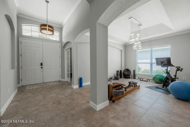 foyer entrance with ornamental molding, a textured ceiling, a chandelier, and light tile patterned floors