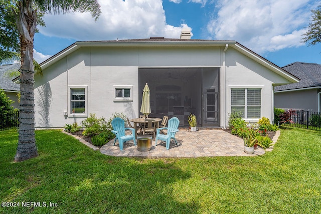 rear view of property featuring a patio area, a lawn, and a sunroom