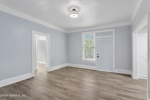 empty room with a textured ceiling, ornamental molding, and hardwood / wood-style flooring