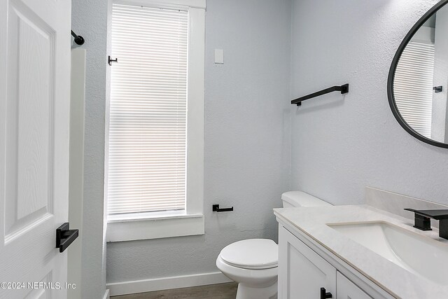 bathroom featuring hardwood / wood-style floors, vanity, a healthy amount of sunlight, and toilet