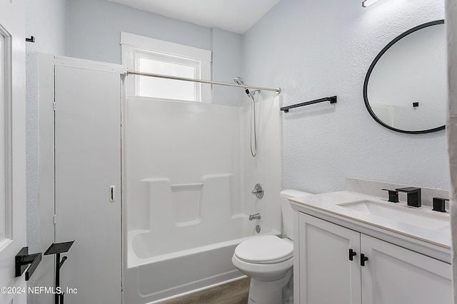 full bathroom with a textured wall, toilet, wood finished floors, vanity, and  shower combination