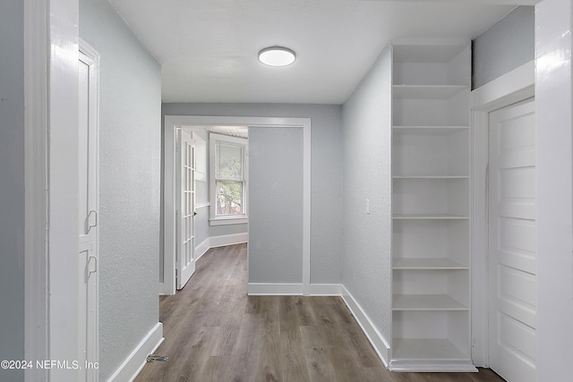 corridor with a textured wall, baseboards, and wood finished floors