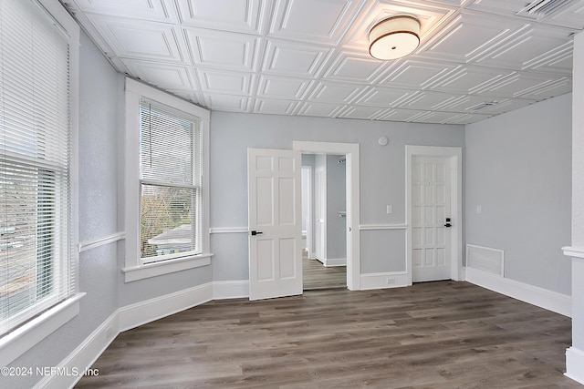 empty room with an ornate ceiling, visible vents, and baseboards