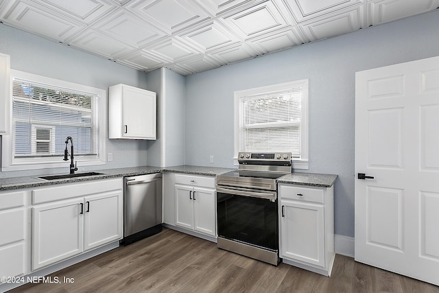 kitchen with white cabinets, an ornate ceiling, appliances with stainless steel finishes, wood finished floors, and a sink