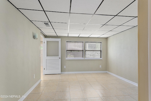 tiled spare room featuring a drop ceiling