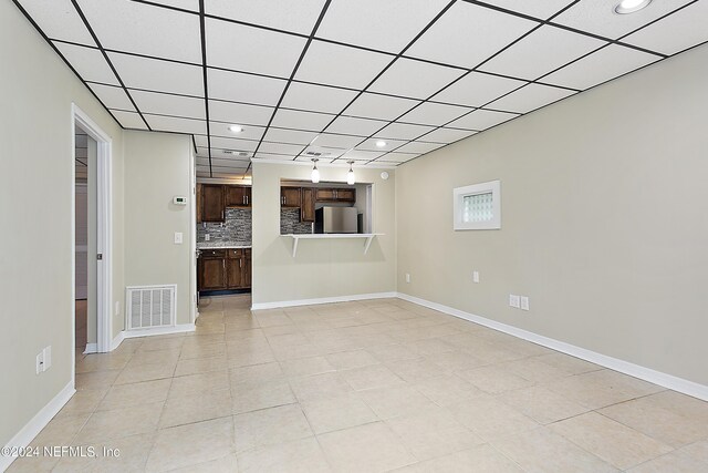 unfurnished living room with light tile patterned floors and a paneled ceiling