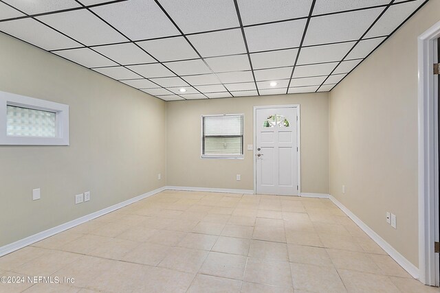 unfurnished room featuring a drop ceiling and light tile patterned floors