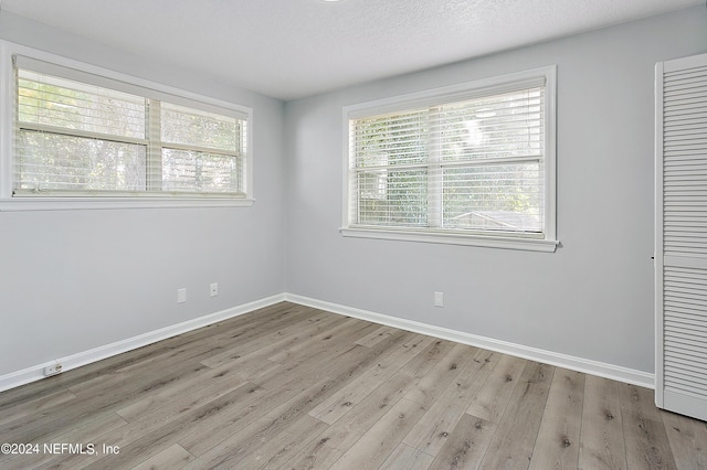 unfurnished room with a wealth of natural light, baseboards, and wood finished floors