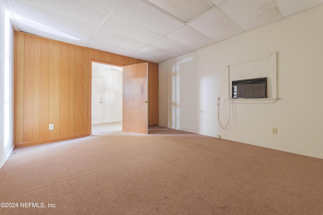 spare room with a wall mounted air conditioner, a drop ceiling, wood walls, and carpet flooring