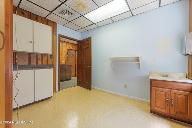 interior space with a paneled ceiling, sink, and light carpet