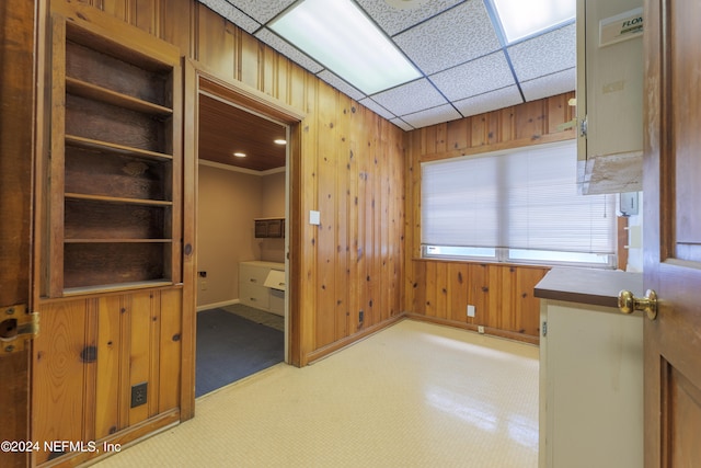 carpeted spare room with wood walls and a drop ceiling