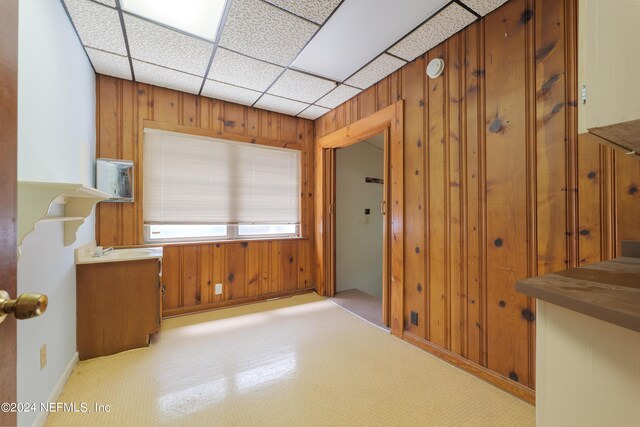 interior space with a paneled ceiling and wood walls