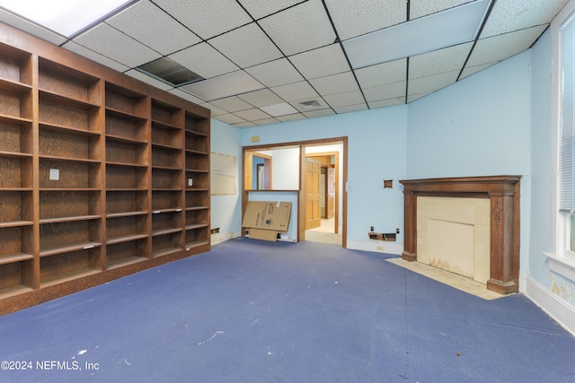 interior space with a paneled ceiling and carpet flooring