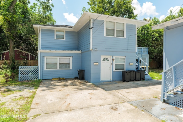 view of front of home featuring a patio area, fence, and stairway