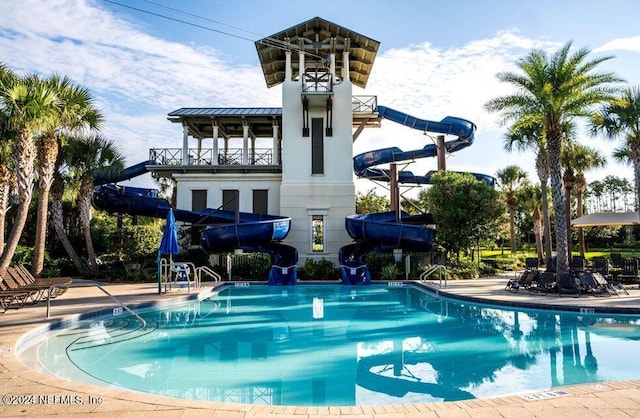 community pool featuring a water slide and a patio area