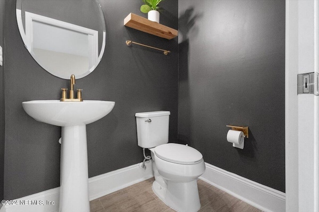 half bathroom with baseboards and toilet