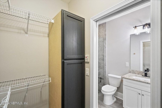 bathroom featuring baseboards, vanity, toilet, and wood finished floors