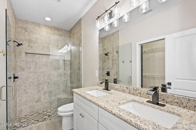 bathroom with double vanity, a stall shower, a textured ceiling, and a sink