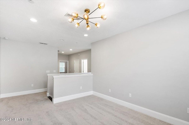 empty room with light carpet, baseboards, a notable chandelier, and recessed lighting