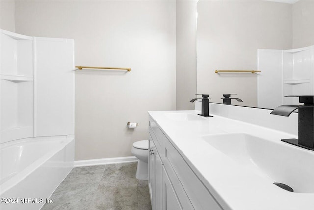 full bath featuring double vanity, a sink, toilet, and baseboards