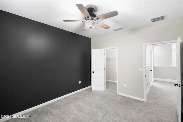 unfurnished bedroom with a walk in closet, carpet, visible vents, and baseboards