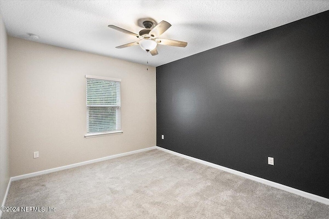 unfurnished room with a textured ceiling, carpet, a ceiling fan, and baseboards