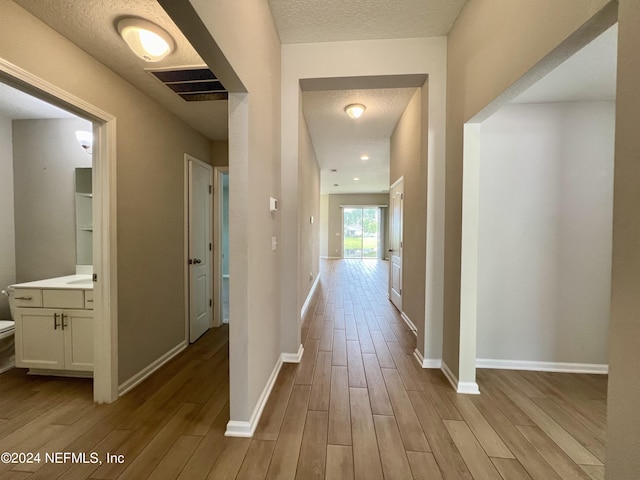 hallway featuring a textured ceiling and light hardwood / wood-style flooring