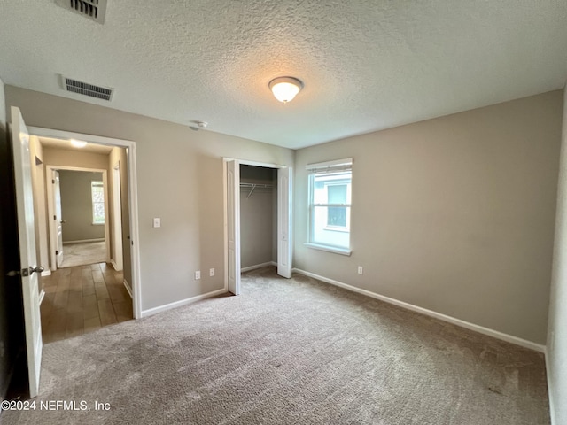 unfurnished bedroom featuring carpet floors, a closet, and a textured ceiling