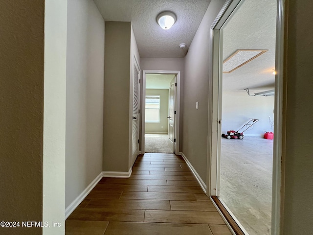 corridor featuring wood-type flooring and a textured ceiling