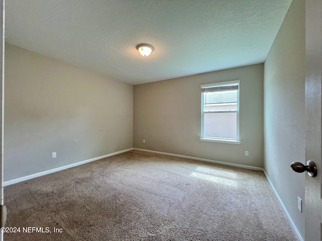 carpeted empty room featuring a textured ceiling