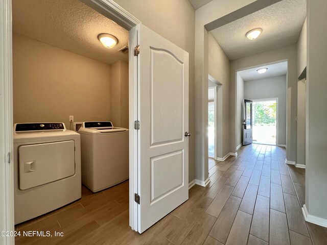 clothes washing area with washer and clothes dryer and a textured ceiling