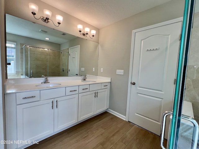 bathroom featuring wood-type flooring, a shower with shower door, vanity, and a textured ceiling