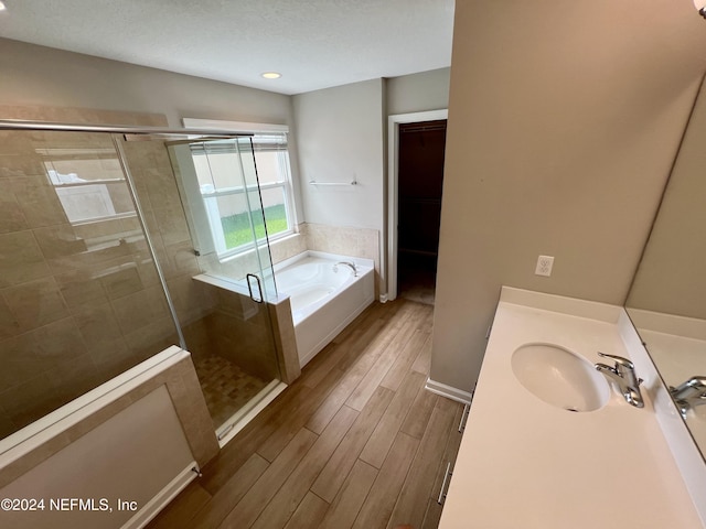 bathroom with hardwood / wood-style flooring, plus walk in shower, and vanity