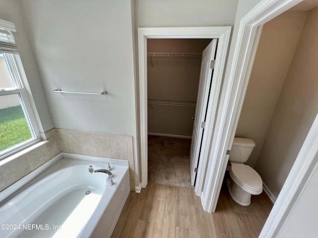 bathroom with hardwood / wood-style flooring, toilet, and a washtub