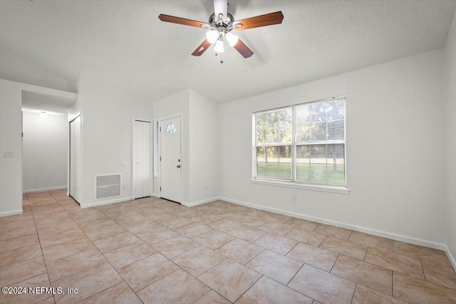 unfurnished room featuring a textured ceiling, ceiling fan, and light tile patterned floors