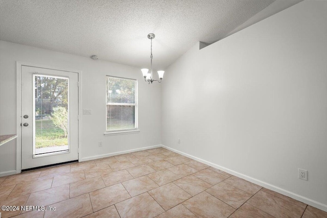 tiled spare room featuring an inviting chandelier and a textured ceiling