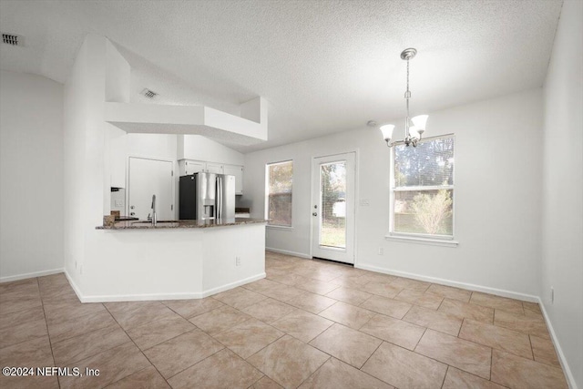 kitchen with a chandelier, kitchen peninsula, stainless steel refrigerator with ice dispenser, sink, and light tile patterned floors