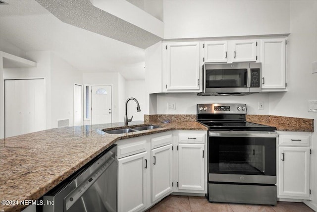 kitchen featuring dark stone countertops, a textured ceiling, white cabinets, appliances with stainless steel finishes, and sink