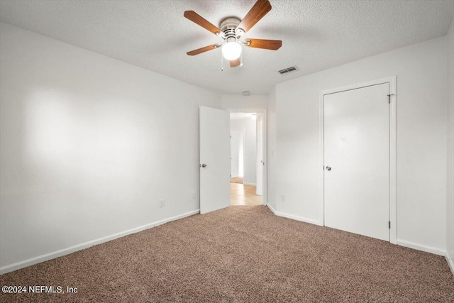 unfurnished bedroom featuring a textured ceiling, carpet floors, and ceiling fan