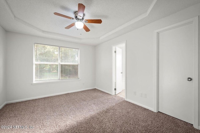 carpeted empty room with a tray ceiling, a textured ceiling, and ceiling fan