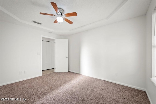 unfurnished room with carpet, ceiling fan, and a tray ceiling