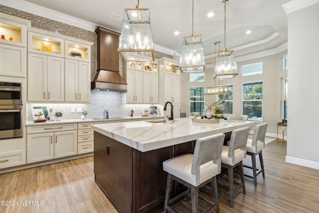 kitchen with custom exhaust hood, sink, pendant lighting, and a spacious island