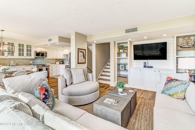 living room featuring light wood-type flooring, visible vents, stairway, and recessed lighting